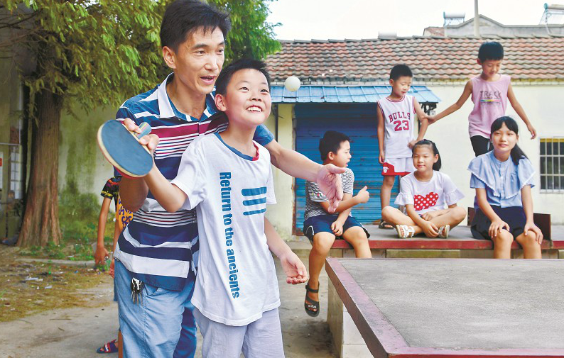 圖為：洪湖市濱湖辦事處洪獅小學(xué)內(nèi)，老師周永杰義務(wù)幫學(xué)生補(bǔ)習(xí)數(shù)學(xué)之余，教孩子們打乒乓球 楚天都市報(bào)記者劉中燦攝